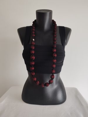 Collier sautoir Naïla en taffetas rouge bordeaux de 2 cm de diamètre, présenté simple, fermoir devant, sur un buste noir.
