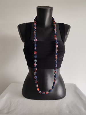 Sautoir perles de coton fleuri rouge et blanc sur fond bleu marine présenté porté en long sur buste noir