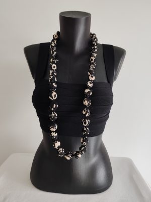 Collier sautoir modulable en perles de coton fleuri blanc sur fond noir, de 2 cm de diamètre.